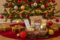 Gift basket with snacks in front of a decorated Christmas tree. Pecans Honey butter, praline, and coffee.