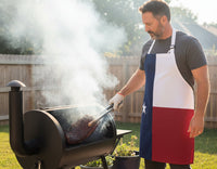 Man wearing a Texas flag apron cooking on a grill outdoors